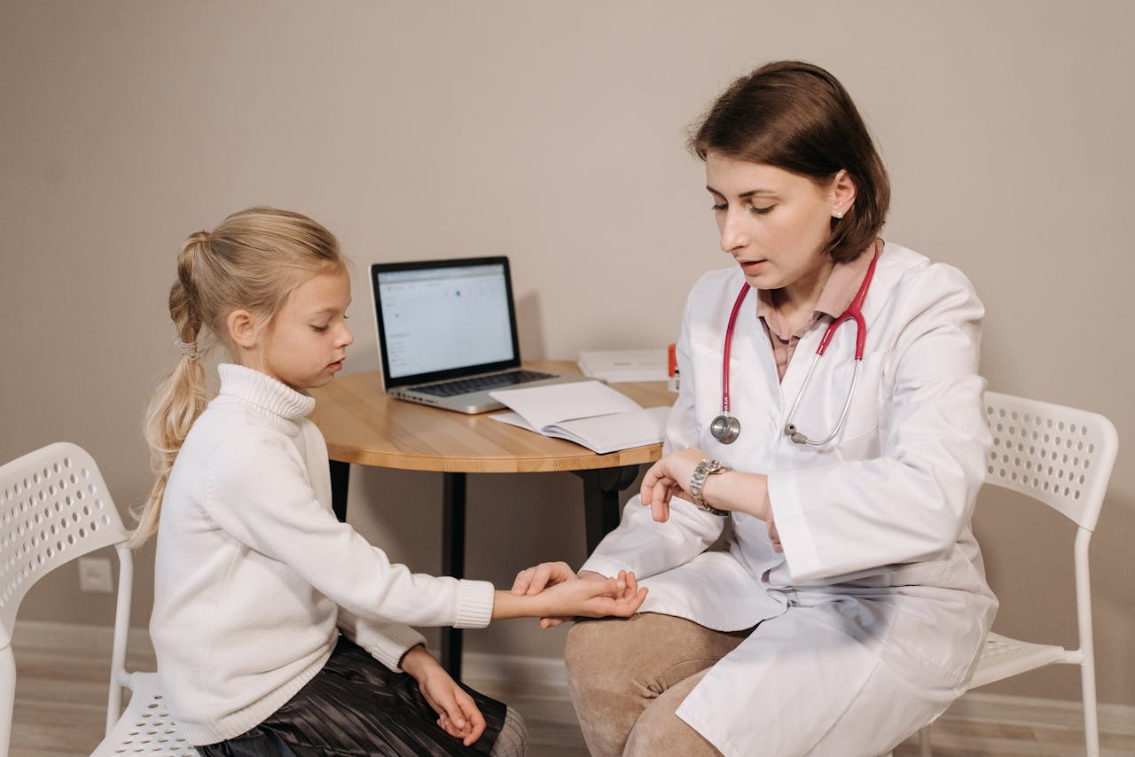 hero-img-02 A doctor examines a young girl during a pediatric consultation in an indoor clinic setting.