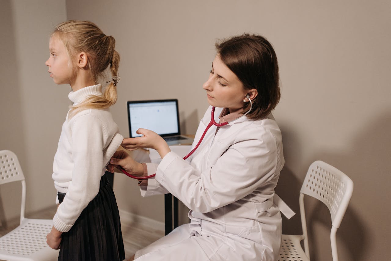 about-01 A doctor uses a stethoscope during a child's medical exam in a clinic setting.