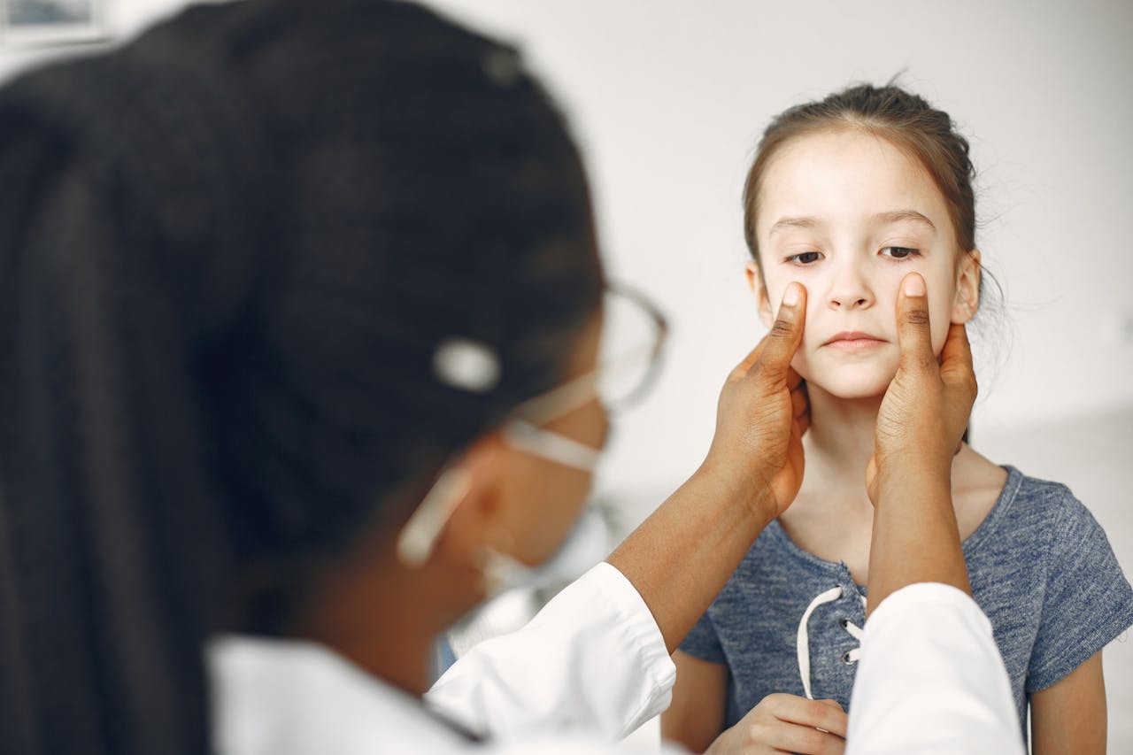 gallery-4 A female doctor carefully examines a young girl's face during a medical checkup.