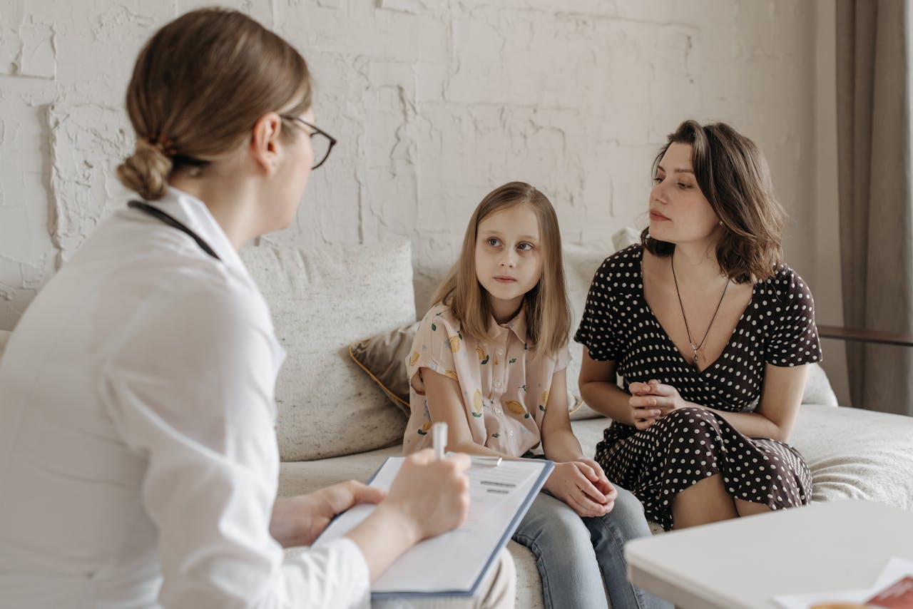 gallery-6 A mother and daughter consult with a doctor during a medical appointment indoors.